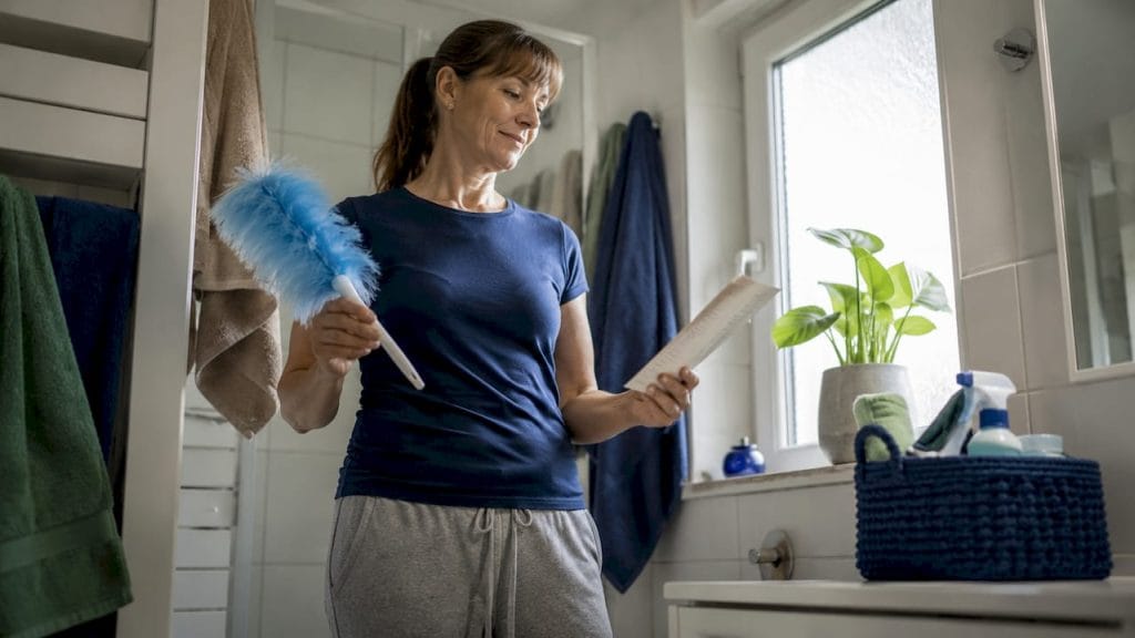 En kvinna som städar sitt kök och bockar av punkter på sin städlista.