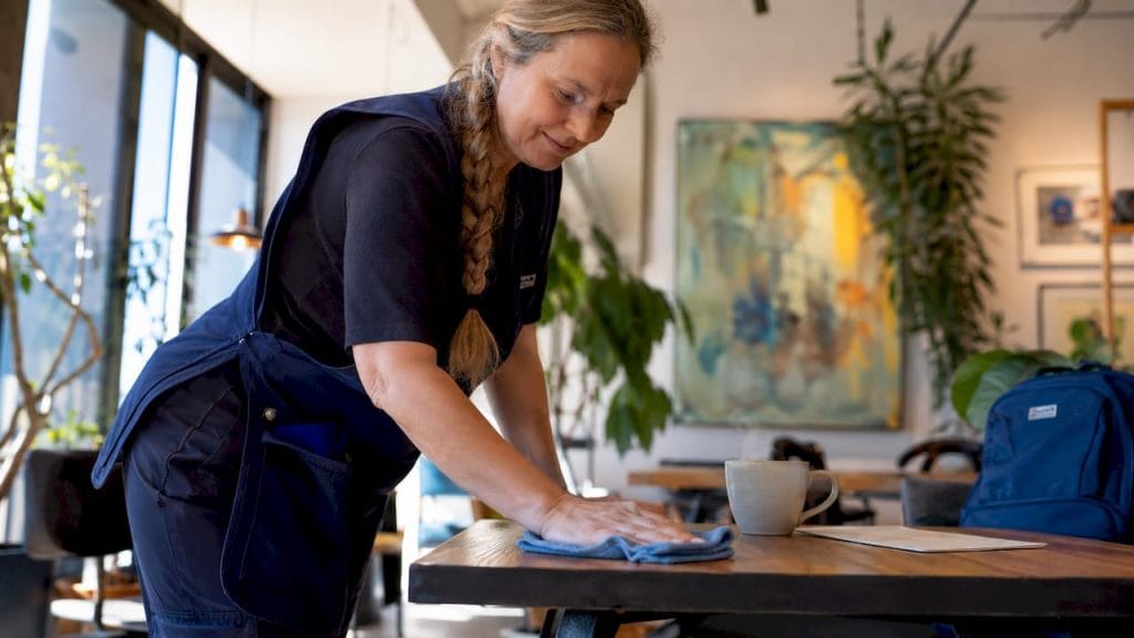Städaren torkar av skrivbordet och rengör tangentbordet på kontoret.